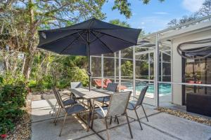 Una mesa y sillas con una sombrilla en un patio. en Avenida Sanctuary, en Siesta Key