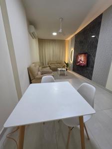 a white table and chairs in a living room at Opera43 Spacious & Central in Ghubrah +2 photos