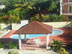 un cenador con techo junto a una piscina en Nely y Pietro share apartment, en Punta Cana