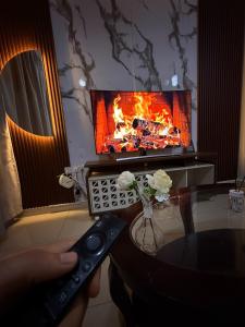 a person holding a remote control in front of a fireplace at Opera47 Spacious & Central in Ghubrah