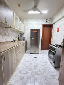 a kitchen with a refrigerator and a stove at Opera47 Spacious & Central in Ghubrah +9 photos