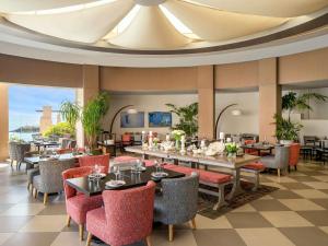 a restaurant with tables and chairs and a ceiling at Novotel Bahrain Al Dana Resort in Manama