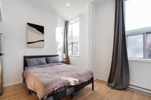 ein Schlafzimmer mit einem Bett und zwei Fenstern in der Unterkunft Studio style pour 2- Location par Semaine-Parking gratuit in Montreal