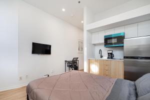 ein Schlafzimmer mit einem Bett und eine Küche mit einem Kühlschrank in der Unterkunft Studio style pour 2- Location par Semaine-Parking gratuit in Montreal