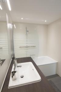 ein Badezimmer mit einem weißen Waschbecken und einer Badewanne in der Unterkunft Vienna Apartments Hauptbahnhof in Wien