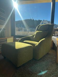 ein Stuhl und ein Ottomane in einem Raum mit einem Fenster in der Unterkunft Sunny Escape Bjelašnica in Ivišovo Greblje