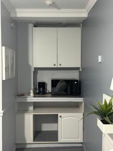 a kitchen with white cabinets and a microwave at Motel Le Refuge in Sherbrooke