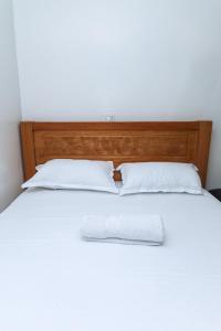 - un lit blanc avec une tête de lit en bois et des oreillers blancs dans l'établissement Kasarani Studio Apartment, à Nairobi