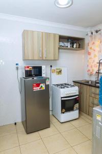 La cuisine est équipée d'une cuisinière, d'un réfrigérateur et d'un four micro-ondes. dans l'établissement Kasarani Studio Apartment, à Nairobi