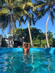 皮帕Padang Hostel的棕榈树游泳池里的人