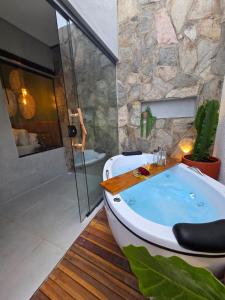 y baño con bañera y pared de piedra. en Pousada Alkamar, en Maragogi