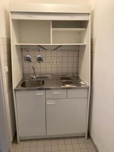 een kleine witte keuken met een wastafel en een aanrecht bij Monteur- oder Wandererwohnung im Hildesheimer Wald in Diekholzen