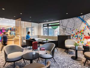 a woman sitting in a waiting room with tables and chairs at ibis Paris Avenue d'Italie 13ème in Paris +117 photos