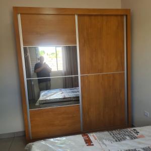 a wooden cabinet with a mirror in a room at Montebelle casa1 in Porangaba