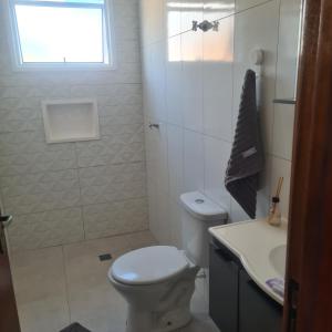 a white bathroom with a toilet and a sink at Montebelle casa1 in Porangaba +3 photos