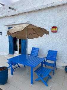 a blue picnic table with an umbrella and two chairs at Beachfront villa sidi ouarzeg in Sidi Ouarsik