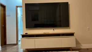 een woonkamer met een grote televisie aan de muur bij Jardim dos Ipês in Araranguá