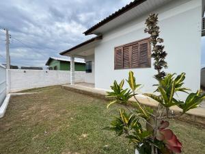 een wit huis met een tuin ervoor bij Jardim dos Ipês in Araranguá