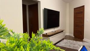 een woonkamer met een flatscreen-tv aan de muur bij Jardim dos Ipês in Araranguá