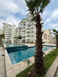 a palm tree in front of a building with a swimming pool at Ocean Park Zenata City Eco in Casablanca
