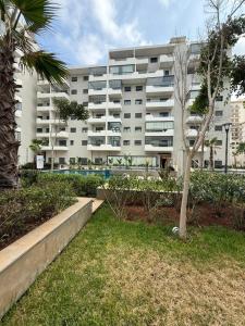 a large white apartment building with a palm tree at Ocean Park Zenata City Eco in Casablanca