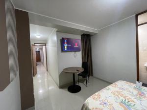 ein Zimmer mit einem Bett, einem Tisch und einem Fernseher in der Unterkunft Agora Hs in Chincha + 4 Fotos
