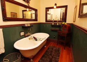 The National Hotel في جيمستاون: حمام مع حوض استحمام أبيض وجدار أخضر