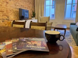 a coffee cup and a magazine on a wooden table at Apartament na Starówce in Wałbrzych