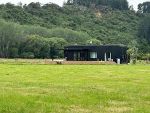a black house in the middle of a field at Bellbird Hideaway in Pleasant Valley