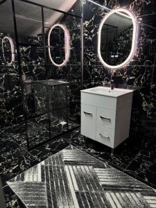 ein schwarzes Badezimmer mit weißem Waschbecken und Spiegeln in der Unterkunft Casa Daiana in Aninoasa + 13 Fotos