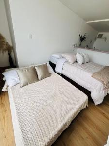 two beds in a room with white walls at Apartaestudio con vista a AV Santander Manizales in Manizales