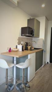 een keuken met een tafel en 2 witte stoelen bij Kj Homes in Prénatier