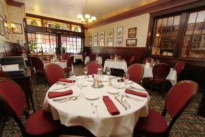 un comedor con mesas blancas y sillas rojas en The National Hotel, en Jamestown