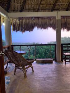 a room with a chair and a balcony with a view at Columpio del Reptil cabaña in Mazunte