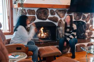 two women sitting in front of a fireplace at Le Repere du Lac - Lake View Access & Spa in Venise-en-Québec