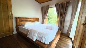een slaapkamer met een groot bed met witte lakens en een raam bij D'Sawah Tetebatu Villas in Tetebatu