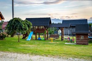 a playground in front of a building with a house at Pocztówka z Mizernej, drewniane domki, widok na Tatry, blisko Velo Czorsztyn, Jezioro Czorsztyńskie, rowery, spokojna okolica in Kluszkowce