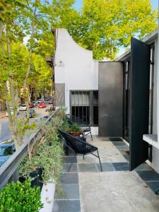 un patio con un banco y árboles y un edificio en Las Glicinas Boutique Apartments, en Colonia del Sacramento