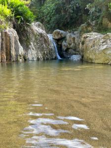 einem Wasserkörper mit einem Wasserfall im Hintergrund in der Unterkunft Glamping Mirador el Túnel in El Cerrito