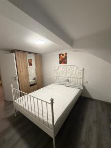 Schlafzimmer mit einem weißen Bett und Holzboden in der Unterkunft Ferienwohnung Nabo in Wadgassen