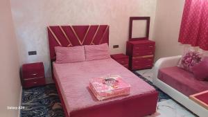 een slaapkamer met een roze bed en een spiegel bij شقق الراحة in Oulad Akkou
