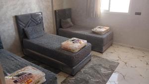 een kamer met 3 bedden, een bank en een raam bij شقق الراحة in Oulad Akkou