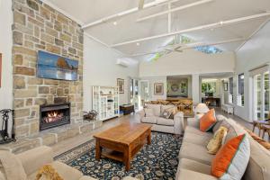 a living room with a large stone fireplace at Brokenback Homestead in Pokolbin