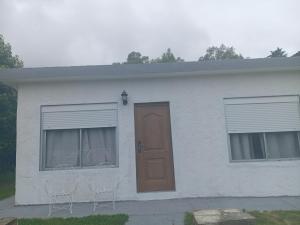 a white house with two chairs and a door at Casa de verano 2 in Piriápolis