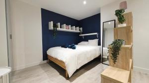 une chambre avec un grand lit avec un mur bleu dans l'établissement Charmissime, à Dunkerque