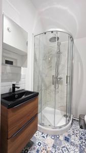 une douche en verre dans une salle de bain avec un lavabo dans l'établissement Charmissime, à Dunkerque 25 autres photos