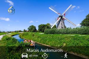 un moulin à vent au milieu d'une rivière avec des gens dans un bateau dans l'établissement Charmissime, à Dunkerque