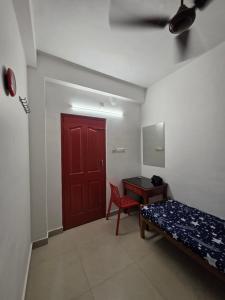 a room with a red door and a bed and a desk at FlexTays Transit - Station Side Stays in Trivandrum