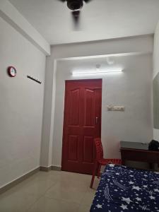 a red door in a room with a bed and a desk at FlexTays Transit - Station Side Stays in Trivandrum +1 photo