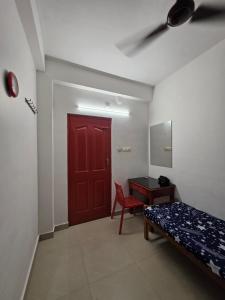 a room with a red door and a bed and a desk at FlexTays Transit - Station Side Stays in Trivandrum